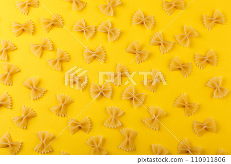 Different types and shapes of dry italian pasta on a yellow background 110911806