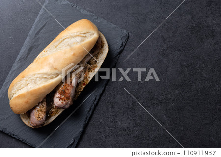 Traditional choripan, Argentina sandwich with chorizo and chimichurri sauce on black slate background 110911937