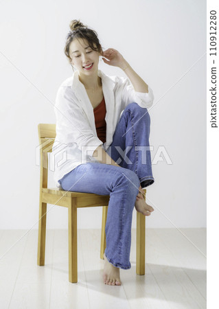Full body portrait of a young woman sitting on a chair, vertical position 110912280