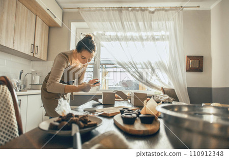 A food blogger shoots fresh chocolate muffins on his phone, prepares content for social networks in the form of photos and videos 110912348