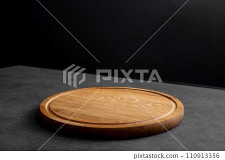 Empty wood round cutting board on black background 110913356