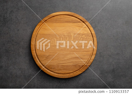 Empty wood round cutting board on black background Empty wood round cutting board on black background 110913357