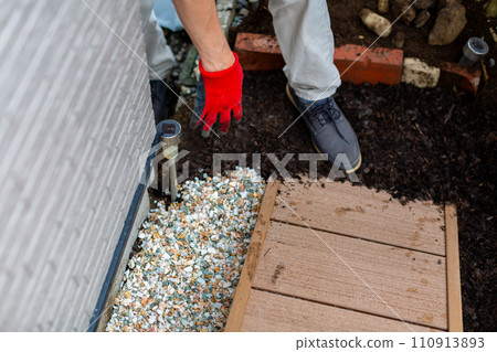 A man laying gravel in the garden, gardening 110913893