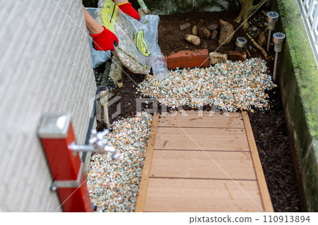 A man laying gravel in the garden, gardening 110913894
