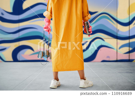 Cropped image of street artist with spray paint can and respirator mask in hands near colorful graffiti wall 110916689