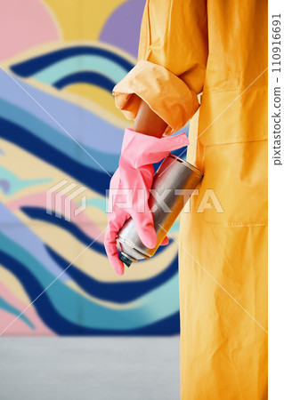Cropped image of street artist with spray paint can in hand near colorful graffiti wall Cropped image of street artist with spray paint can in hand near colorful graffiti wall 110916691