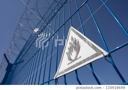 A fence with barbed wire and a triangle sign is extremely flammable. SDOF 110916699