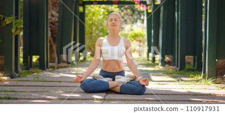 idea of healthy lifestyle and sports in a modern city. Female jogger. Fit young Caucasian woman stretching muscle in park before running and enjoying healthy outdoor. Fitness girl in public park. 110917931
