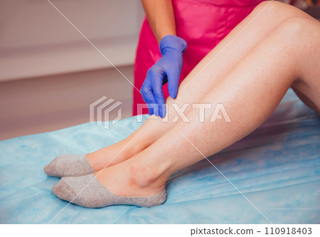 The beautician is preparing for depilation and applying the cream The beautician is preparing for depilation and applying the cream 110918403