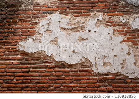 Old brick wall with large piece of stucco in the middle 110918856