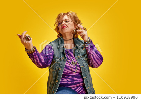 Portrait of directive mature woman dressed retro clothes posing looking away against yellow background. 110918996