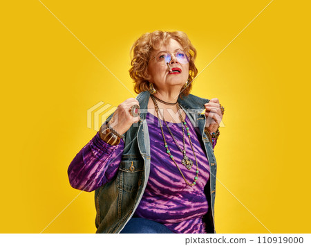 Portrait of attractive vibrant woman who smoking dressed vintage style outfit and retro jewels posing against vivid yellow background. 110919000
