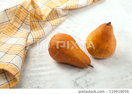 Pears and yellow kitchen towel on white wooden background.. 110919056