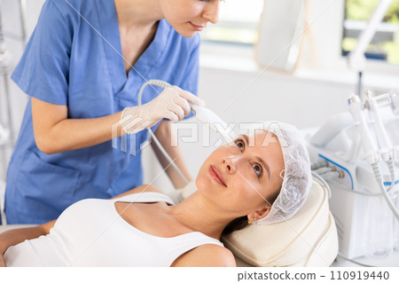 Young woman cosmetologist doing exfoliation procedure to young woman Young woman cosmetologist doing exfoliation procedure to young woman 110919440