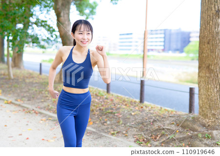 Young woman jogging along the tree line, diet, body makeup, running wear, sports bra 110919646