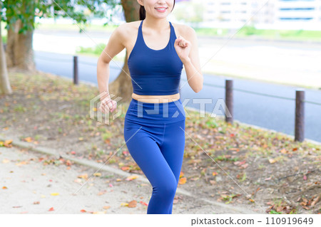 Young woman jogging along the tree line, diet, body makeup, sports bra, faceless, trimmed up Young woman jogging along the tree line, diet, body makeup, sports bra, faceless, trimmed up 110919649