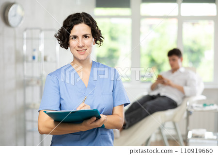 Middle-aged woman doctor posing in doctor's cabinet with document in hands Middle-aged woman doctor posing in doctor's cabinet with document in hands 110919660