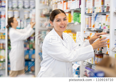 Woman seller puts medical cosmetics and other body care products on shelves Woman seller puts medical cosmetics and other body care products on shelves 110919710