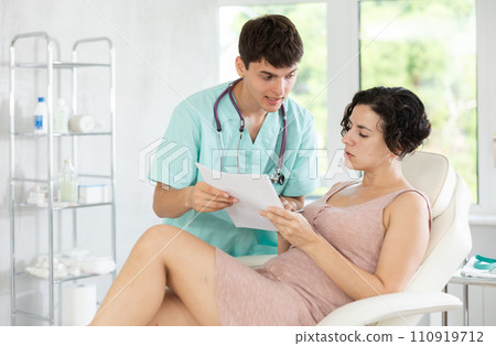 Friendly cosmetologist doctor offers woman patient to sign contract before the operation in beauty clinic 110919712