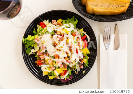 spanish lettuce salad with sauce and bacon in black plate for dinner spanish lettuce salad with sauce and bacon in black plate for dinner 110919755