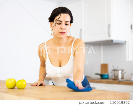 Latin american woman cleaning kitchen countertop with rag and spray Latin american woman cleaning kitchen countertop with rag and spray 110919802