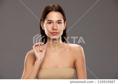Portrait of beautiful young woman hosing skin moisturizing ampule against studio background 110919987