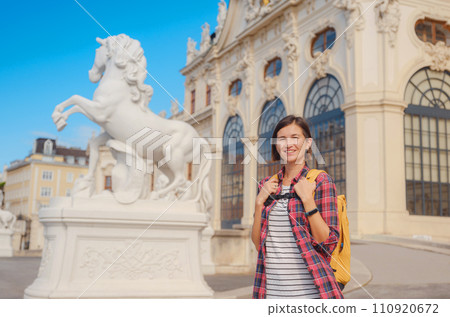 Female tourist traveling in Austria, capital city Vienna. summer female solo trip to Europe, happy young woman walking in park near Belvedere palace complex in Baroque style. 110920672