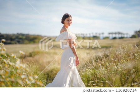 Beautiful Asian young woman in white dress outdoor in flower field. embracing fresh air and engaging in outdoor activities. Friluftsliv concept means spending as much time outdoors as possible 110920714