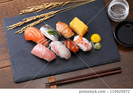 黑石盤上的握壽司，配有清酒和稻穗 110920972