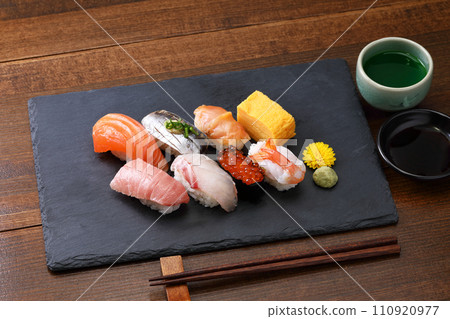 Nigiri sushi arranged on a black stone plate with green tea Nigiri sushi arranged on a black stone plate with green tea 110920977