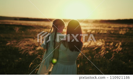 Mommy and daughter discuss going to first grade while walking in field 110921186
