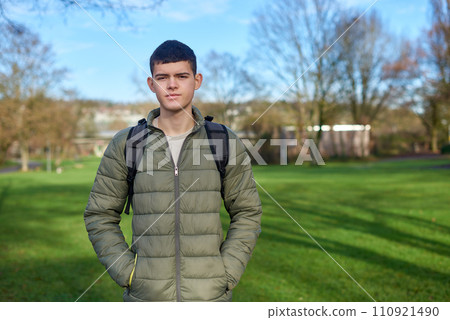 Youthful Elegance: Beautiful 17-Year-Old Boy Standing in the Autumn Park with Lush Green Lawn 110921490