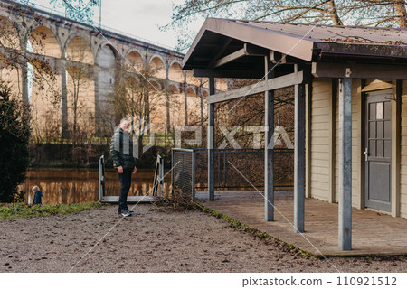 Timeless Elegance: 40-Year-Old Man in Stylish Jacket by Neckar River and Historic Bridge in Bietigheim-Bissingen, Germany 110921512