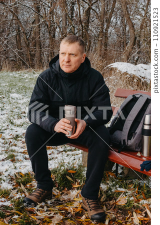 Winter Serenity: 40-Year-Old Man Enjoying Tea on Snow-Covered Bench in Rural Park. Immerse yourself in the tranquil beauty of winter as a 40-year-old man finds solace on a snowy bench in a rural park. Winter Serenity: 40-Year-Old Man Enjoying Tea on Snow-Covered Bench in Rural Park. Immerse yourself in the tranquil beauty of winter as a 40-year-old man finds solace on a snowy bench in a rural park. 110921523