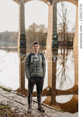 Youthful Exploration: 17-Year-Old Teen in Stylish Jacket by Neckar River and Historic Bridge in Bietigheim-Bissingen, Germany 110921530