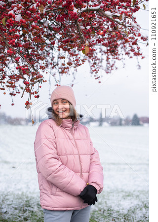 Winter Elegance: Portrait of a Beautiful Girl in a Snowy European Village. Winter lifestyle portrait of cheerful pretty girl. Smiling and having fun in the snow park. Snowflakes falling down Winter Elegance: Portrait of a Beautiful Girl in a Snowy European Village. Winter lifestyle portrait of cheerful pretty girl. Smiling and having fun in the snow park. Snowflakes falling down 110921651