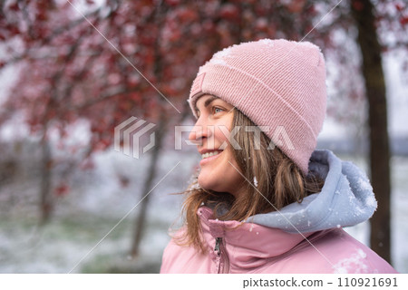 Winter Elegance: Portrait of a Beautiful Girl in a Snowy European Village. Winter lifestyle portrait of cheerful pretty girl. Smiling and having fun in the snow park. Snowflakes falling down Winter Elegance: Portrait of a Beautiful Girl in a Snowy European Village. Winter lifestyle portrait of cheerful pretty girl. Smiling and having fun in the snow park. Snowflakes falling down 110921691