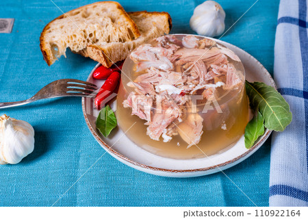 Jelly with meat, beef aspic, traditional dish. portion on plate. Bread and chili. 110922164