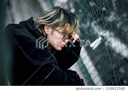 一個戴著墨鏡的年輕人坐在路上 110922560