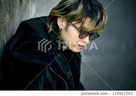 A young man wearing sunglasses sitting on the road 110922561
