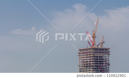 Tower cranes working on the construction site of new skyscraper high-rise building aerial timelapse. Dubai Tower cranes working on the construction site of new skyscraper high-rise building aerial timelapse. Dubai 110922901