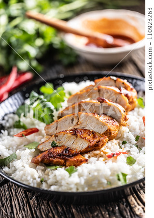 Grilled chicken breast served in a pan with jasmine rice and chili peppers 110923263