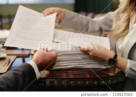 Hands of unrecognizable caucasian male and female lawyers passing documents to each other 110923562