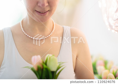Jewelry gift. Pearl necklace on woman with flowers 110924076
