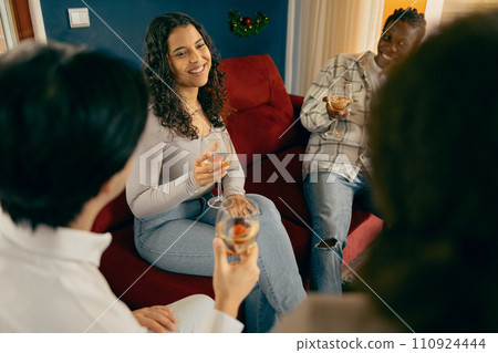 Group of smiling friends enjoying in conversation and drinking wine during Christmas party at home 110924444