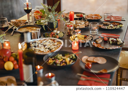 Cozy holiday table setting with different delicious food and beverages ready for friends home party Cozy holiday table setting with different delicious food and beverages ready for friends home party 110924447