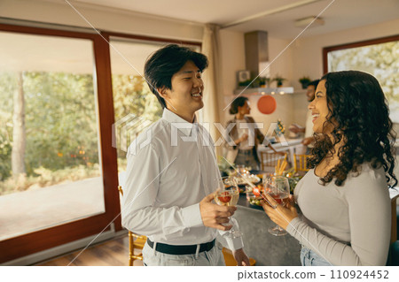Group of smiling friends enjoying in conversation and drinking wine during holiday party at home 110924452