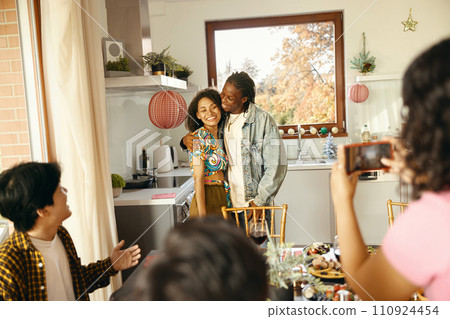 Woman making photo on phone for happy friends couple during festive home party 110924454