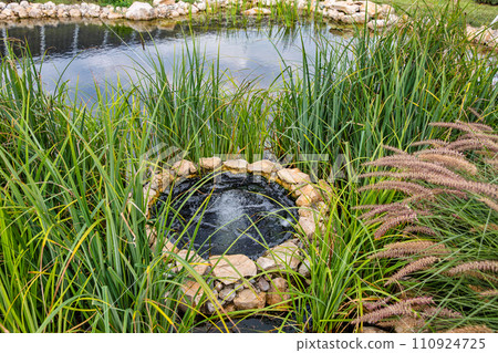 Landscape with small lake and open well Landscape with small lake and open well 110924725