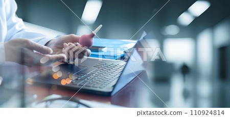 Female doctor demonstrates enema in office with laptop computer. Female doctor demonstrates enema in office with laptop computer. 110924814
